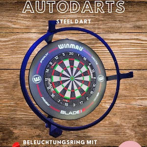 Op de afbeelding: Een Winmau Autodarts stalen dartbord met een blauwe rand en een rood, groen en zwart doel. Het bord heeft het Winmau-logo en de tekst "STEEL DART". Twee rode darts staan ​​onderaan. De tekst "BELEUCHTUNGSRING MIT KAMERAHALTER" is ook zichtbaar.