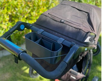 Può includere: Un passeggino nero con un organizer e parasole integrati. L'organizer ha più scomparti. Il manico del passeggino ha un accento blu. L'immagine include il testo "Happy Druck 3D Printing".