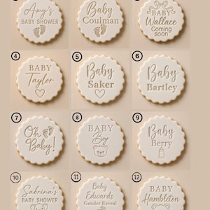Puede incluir: Una colecci&oacute;n de doce galletas redondas blancas con bordes festoneados, cada una grabada con textos y gr&aacute;ficos &uacute;nicos sobre beb&eacute;s, incluyendo nombres como Amy's, Taylor y Saker, junto con iconos de huellas, corazones, un biber&oacute;n y ositos de peluche.