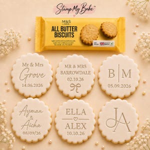 May include: Six round, scalloped-edge biscuits with custom embossed text and dates, arranged below a yellow M&S All Butter Biscuits packet. The biscuits feature various designs including names, initials, and wedding dates in a serif or script font.