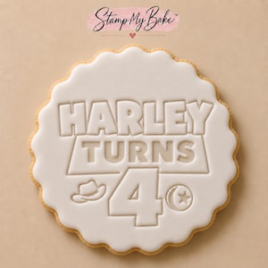 May include: A round, scalloped-edge biscuit with white icing featuring the embossed text "HARLEY TURNS 4" in a bold, block font. Below the text, a small cowboy hat icon and a circular sheriff badge icon with a star are clearly visible.