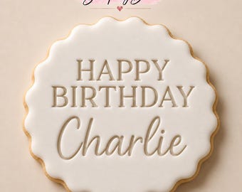 May include: A round scalloped cookie with smooth white icing featuring the embossed text "HAPPY BIRTHDAY Charlie" in the center. Above the cookie, the text "Stamp My Bake" is displayed with a small heart icon in a pink brush stroke.