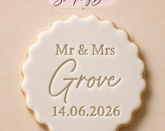 May include: A round scalloped cookie topped with smooth white icing. The text "Stamp My Bake" appears at the top. The center features the embossed text "Mr & Mrs Grove" followed by the date "14.06.2026" in a clean, centered font.