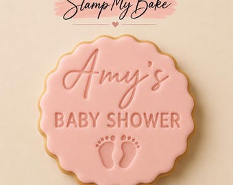 May include: A round, scalloped-edge cookie with light pink icing. The text 'Stamp My Bake' appears at the top. The center features the embossed text 'Amy's BABY SHOWER' above a pair of small, detailed baby footprints.