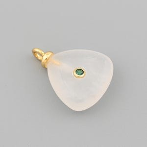 May include: A pendant with a pale pink, triangular stone and a small, round, green gem in the center. The pendant has a gold-colored bail. The background is a solid, light gray.