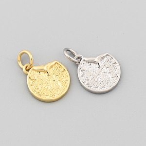 May include: Two small, round pendants. One is gold-colored, the other is silver-colored. Both have a textured surface and a small loop for a chain. The pendants are on a light gray background.