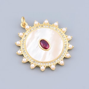 May include: A gold-colored pendant with a central oval-shaped red gemstone. The pendant features a white, circular mother-of-pearl center, surrounded by a ring of small clear stones and pearls. The design resembles a sunburst.