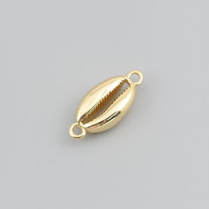 May include: A gold-toned metal jewellery connector shaped like a cowrie shell. The charm features a smooth, polished surface with a central slit and a small circular loop attached to each end for connecting to chains or other jewellery components.