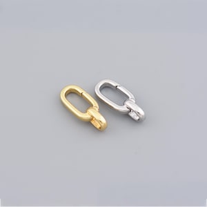 Puede incluir: Dos cierres ovalados, uno dorado y otro plateado, sobre un fondo gris. Los cierres presentan un mecanismo de bisagra para un cierre seguro, ideal para la creación de joyas o proyectos de artesanía. Miden unos 2 cm de largo.