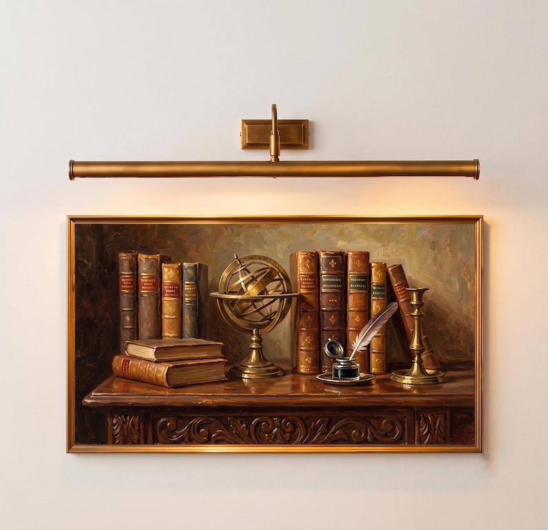 May include: A rectangular wall-mounted brass picture light fixture positioned above a framed oil painting. The painting depicts a dark wooden desk with several leather-bound books, a brass armillary sphere, an inkwell with a quill, and a candlestick.