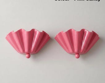 May include: Two pink candy colored wall sconces with a pleated, fan-like design. Each fixture features a semi-circular, ruffled shade with a smooth finish and a small, spherical accent at the base. The text Colour - Pink Candy is visible.