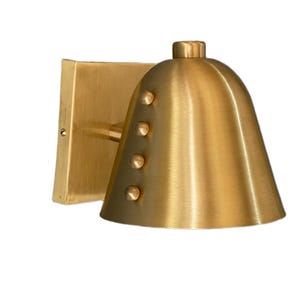 May include: A brass-colored wall sconce with a bell-shaped shade and a square backplate. The shade has four small, round rivets. The fixture is made of metal and has a brushed finish. The sconce is designed for indoor lighting.