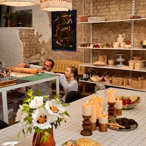 Behind-the-scenes look at the MaVroni Studio workshop, showing unfired clay pieces on shelves and the handcrafted process. This highlights the authentic, artisan quality of the pottery, from the first touch of clay to the finished functional art.