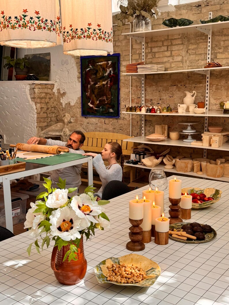 Behind-the-scenes look at the MaVroni Studio workshop, showing unfired clay pieces on shelves and the handcrafted process. This highlights the authentic, artisan quality of the pottery, from the first touch of clay to the finished functional art.