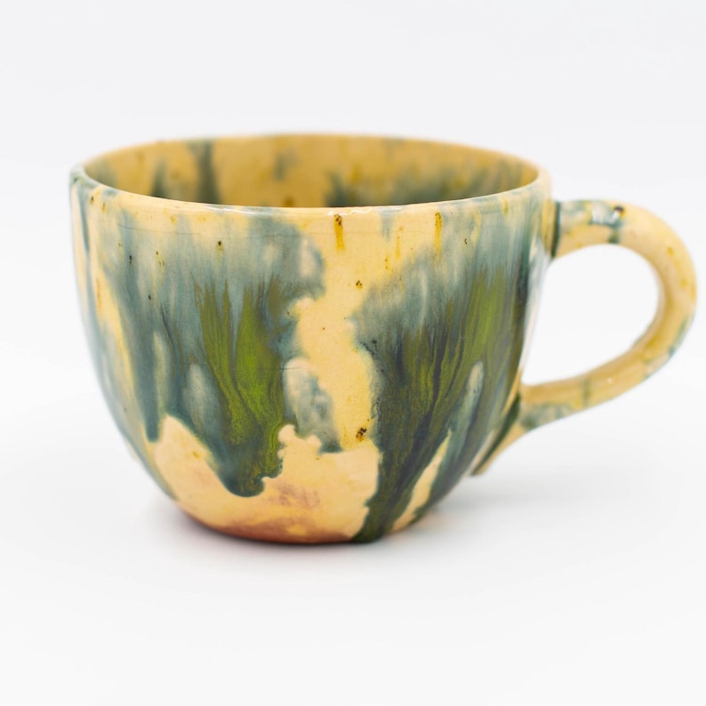Handmade "Deep Ocean" ceramic mug with a unique drip glaze in shades of teal, forest green, and sandy beige. This 17oz artisan coffee cup features organic, flowy textures on red clay, offering a coastal minimalist aesthetic. Perfect as a unique housewarming gift or neutral home decor piece from MaVroni Studio.