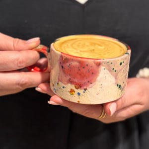 Puede incluir: Juego de tres tazas de cerámica con acabado mate moteado. Las tazas son de color crema, gris claro y gris oscuro. Cada taza tiene un diseño simple y minimalista, ideal para café o té.