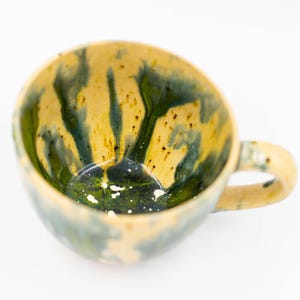 Top-down view of an artisan ceramic mug highlighting the smooth, glossy interior glaze and the unique textured brushstrokes on the exterior.