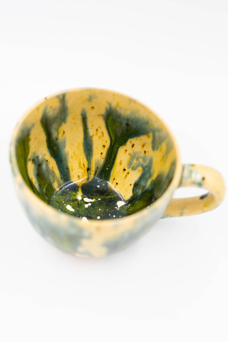 Top-down view of an artisan ceramic mug highlighting the smooth, glossy interior glaze and the unique textured brushstrokes on the exterior.