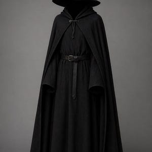 May include: A black hooded cloak and matching pointed hat. The cloak has a long, flowing design with a belt at the waist. The hat has a wide brim and a tall, pointed crown. The outfit is made of a dark, possibly wool-like material.
