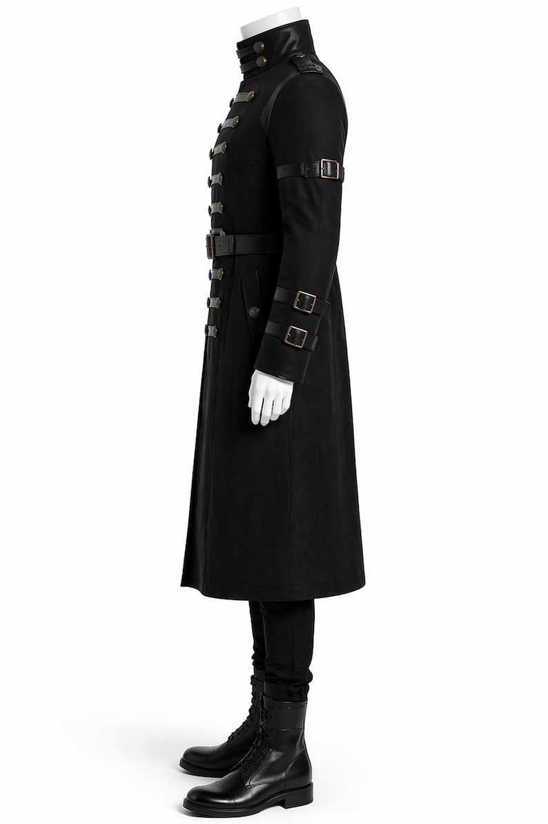 May include: Black military-style coat with multiple button closures, a high collar, and leather accents. The coat features a belt at the waist and straps on the sleeves. The model is wearing black pants and boots.