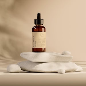 May include: A brown glass dropper bottle with a black cap and a cream-colored label. The bottle is labeled "YOUR BRAND Bottle Design". The bottle is displayed on a stack of white stones, with a neutral background.
