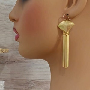 May include: Gold tone earrings with a geometric shape and three dangling bars.