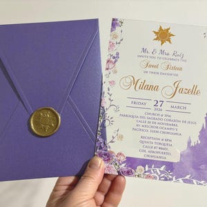 Può includere: Un set di inviti viola per una festa di Sweet Sixteen. L'invito presenta accenti floreali, una silhouette di castello e il testo "Mr. & Mrs. Ruiz vi invitano a celebrare il Sweet Sixteen della loro figlia Milana Jazelle". La busta è sigillata con un sigillo di cera dorata.