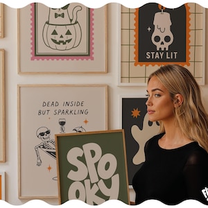 May include: A collection of framed wall art prints featuring Halloween-themed illustrations, including a cat in a pumpkin, a skull with the text STAY LIT, and a skeleton in a martini glass with the text DEAD INSIDE BUT SPARKLING, plus a SPOOKY print.