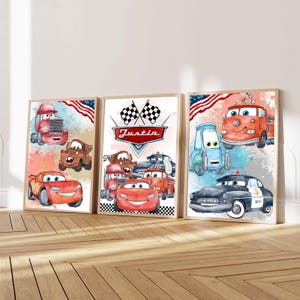 May include: Three rectangular wall art prints featuring watercolour illustrations of anthropomorphic race cars and trucks. The central print displays the name Justin in a red banner beneath two chequered flags, surrounded by various vehicle characters.