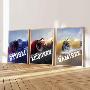 May include: Three rectangular wall art prints featuring Disney Pixar Cars characters. The left print shows a blue Jackson Storm car, the centre print shows a red Lightning McQueen car, and the right print shows a yellow Cruz Ramirez car.