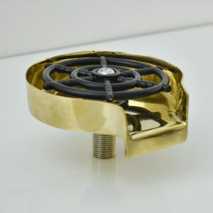 K&ouml;nnte beinhalten: Ein Flaschenverschluss aus Messing mit einem schwarzen Steuerraddesign. Der Verschluss hat einen Gewindesockel zum Einsetzen in eine Flasche und ein gebogenes, offen-seitiges Design.