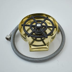 K&ouml;nnte beinhalten: Ein messingfarbener Glasreiniger mit einem schwarzen, kreisf&ouml;rmigen Spr&uuml;hkopf. Ein flexibler, silberfarbener Schlauch ist angebracht. Der Reiniger dient zum schnellen Sp&uuml;len von Gl&auml;sern und Tassen.