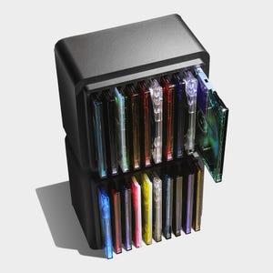 Puede incluir: Una unidad de almacenamiento de plástico negro con dos niveles apilados que contiene múltiples cajas de CD translúcidas y coloridas. Cada caja presenta un tono vibrante, incluyendo azul, rojo, amarillo y morado, dispuestas verticalmente.