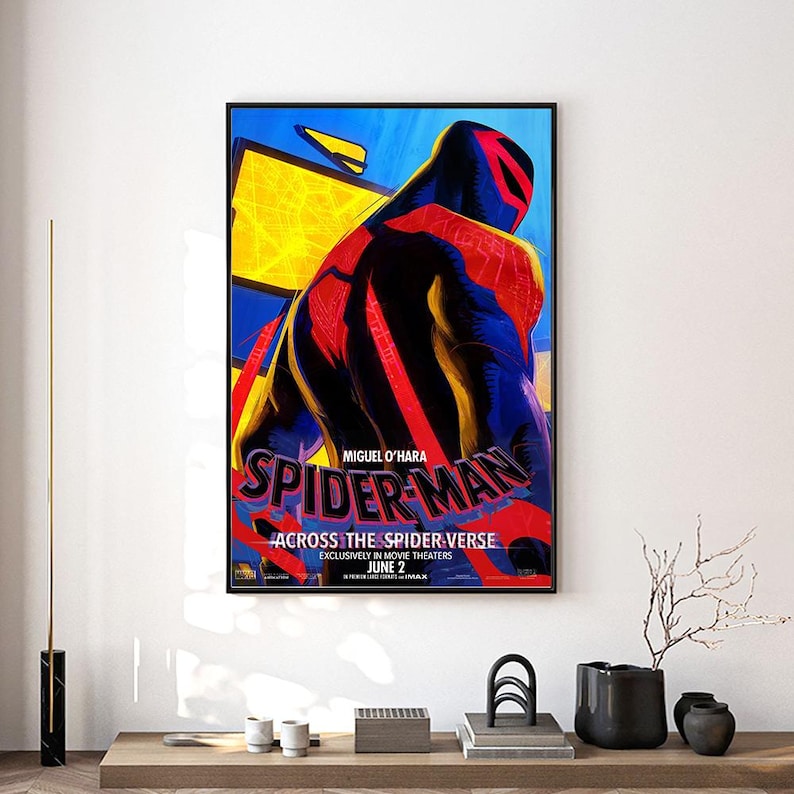 Może przedstawiać: Oprawiony plakat filmowy do filmu "Spider-Man: Across the Spider-Verse" z wystylizowanym wizerunkiem Spider-Mana w czerwono-czarnym kostiumie na ż&oacute;łto-niebieskim tle. Plakat zawiera tekst "Miguel O'Hara" i "June 2".
