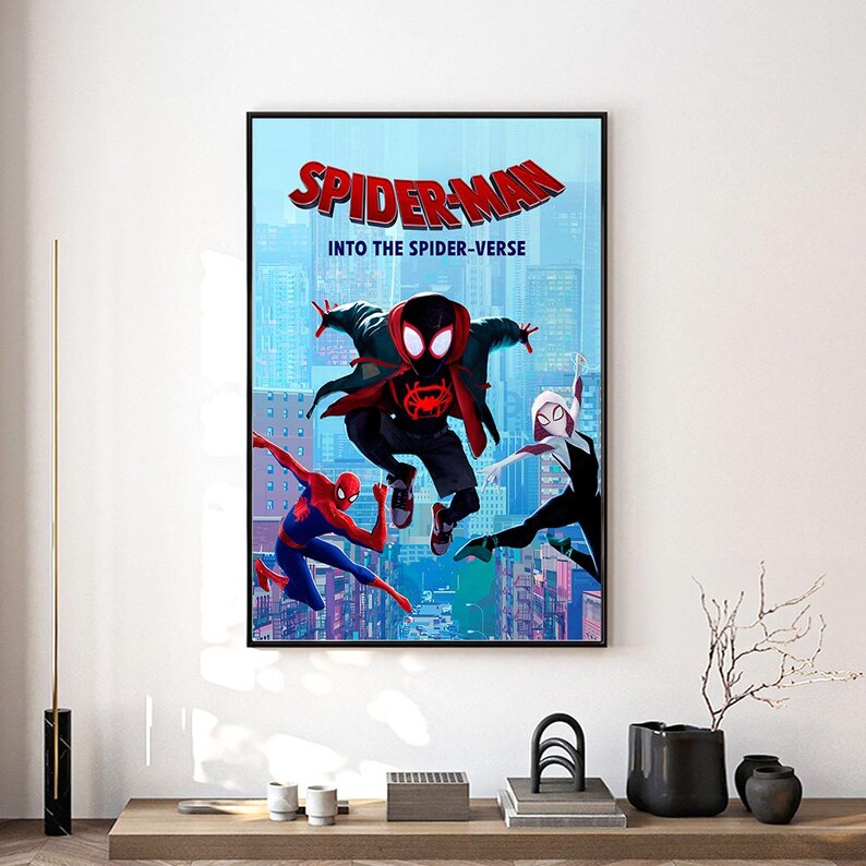 Może przedstawiać: Oprawiony plakat z postaciami Spider-Mana z filmu "Spider-Man: Into the Spider-Verse". Grafika przedstawia Spider-Mana w czerwono-niebieskim kostiumie, Milesa Moralesa i Spider-Gwen na tle panoramy miasta. Tytuł "SPIDER-MAN" jest widoczny.