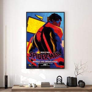 Może przedstawiać: Oprawiony plakat z Spider-Manem z filmu "Across the Spider-Verse". Grafika przedstawia plecy Spider-Mana, w czerwono-czarnym kostiumie na niebiesko-ż&oacute;łtym tle. Tekst zawiera "MIGUEL O'HARA" i "JUNE 2".