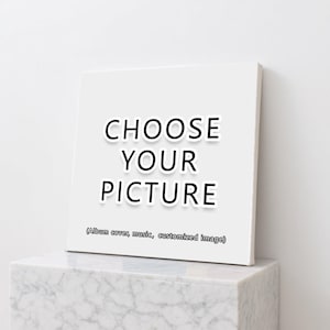 Puede incluir: Un lienzo cuadrado blanco con el texto "CHOOSE YOUR PICTURE" en negrita, en negro. Debajo, la frase "(Album cover, music, customized image)". El lienzo se muestra sobre una superficie de mármol blanco.