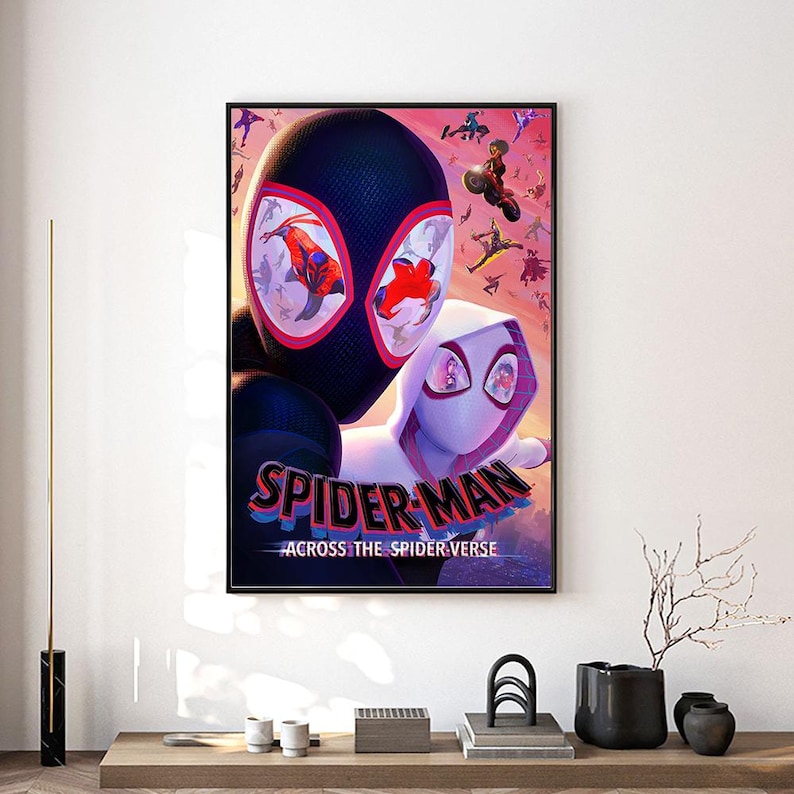 Może przedstawiać: Oprawiony plakat z Spider-Manem i Spider-Gwen z filmu "Spider-Man: Across the Spider-Verse". Plakat ma czarną ramę i wyświetla tytuł dużymi, kolorowymi literami. Tło to żywa mieszanka r&oacute;żu i fioletu.