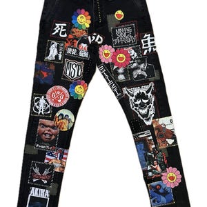 May include: Black denim jeans with various patches featuring Japanese text, cartoon characters, and graphic designs. Patches include a smiling flower, a skull, and the text "MISSING SINCE THURSDAY".