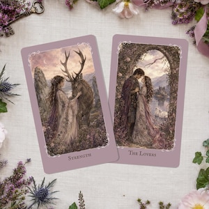 May include: Two tarot cards with fantasy art. One card is labeled "Strength" and depicts a woman with a deer. The other card is labeled "The Lovers" and shows a couple embracing. The cards have a lavender background with ornate borders.