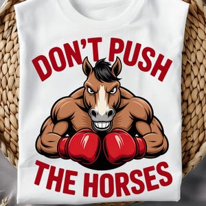 Puede incluir: Camiseta blanca con una ilustración de dibujos animados de un caballo musculoso con guantes de boxeo rojos. El texto "DON'T PUSH THE HORSES" está impreso en rojo encima y debajo de la imagen del caballo.