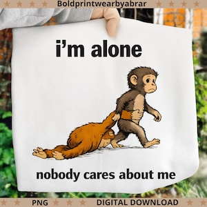 May include: White graphic tee featuring a cartoon monkey pulling another monkey by the waist. The text "I'm alone" and "nobody cares about me" are printed in black.
