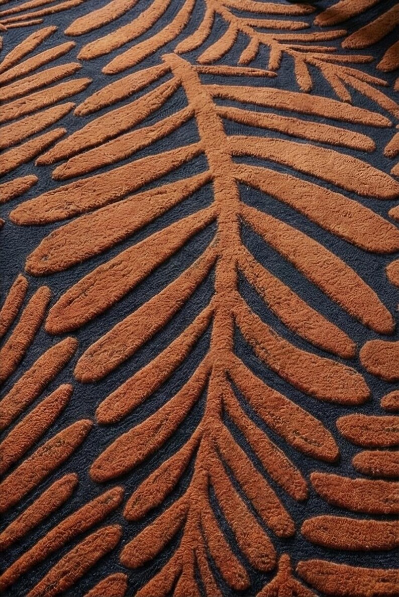 May include: Close-up of a rug with a repeating leaf pattern. The leaves are a warm, rust-orange color and are raised above the dark navy blue background. The rug has a soft, textured appearance.
