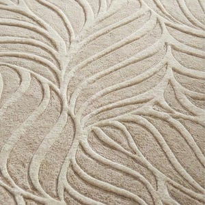 May include: Close-up of a beige rug with a raised leaf pattern. The design features curved, vein-like lines in a lighter shade of beige, creating a textured, three-dimensional effect. The rug's neutral color palette and organic design suggest a natural, modern aesthetic.