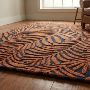 May include: A rectangular area rug with a leaf pattern. The rug features a dark blue background with a raised, textured design in shades of brown. The leaf pattern is arranged in a repeating design across the rug's surface.