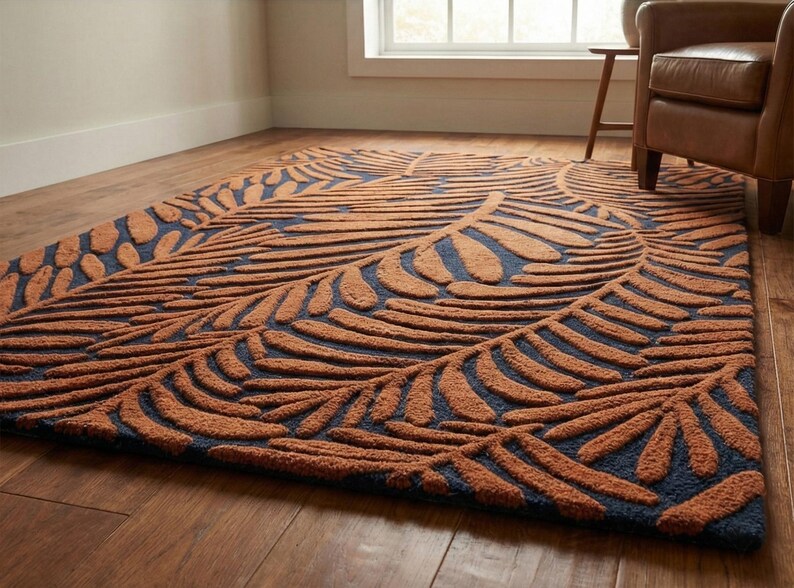 May include: A rectangular area rug with a leaf pattern. The rug features a dark blue background with a raised, textured design in shades of brown. The leaf pattern is arranged in a repeating design across the rug's surface.