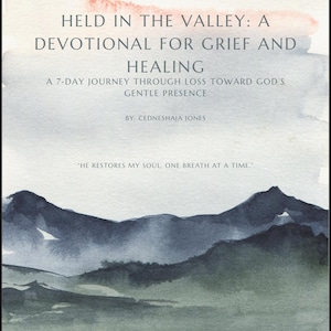 Op de afbeelding: Boekomslag met aquarel kunst van bergen in blauwe en groene tinten. De titel luidt "HELD IN THE VALLEY: A DEVOTIONAL FOR GRIEF AND HEALING." De tekst eronder luidt "A 7-DAY JOURNEY THROUGH LOSS TOWARD GOD'S GENTLE PRESENCE."
