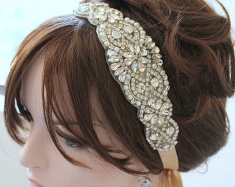 May include: A silver and white beaded headband with a satin ribbon tie. The headband is decorated with rhinestones and pearls.