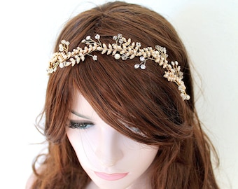 May include: A gold bridal headband with delicate leaves and pearl accents. The headband is worn on a mannequin with long brown hair.