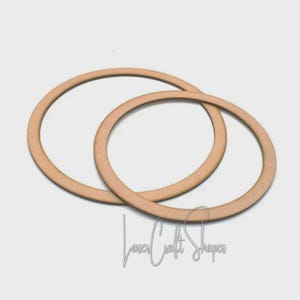 May include: Two light brown wooden circle shapes, one slightly larger than the other, overlapping on a white background. The text "Laser Craft Shapes" is in the lower right corner. These shapes could be used for crafting or DIY projects.
